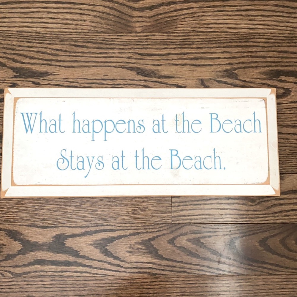 Wooden beach sign “what happens at the beach…”